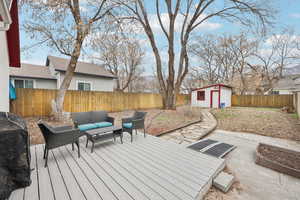 Wooden deck with an outdoor hangout area, a fenced backyard, and a storage unit