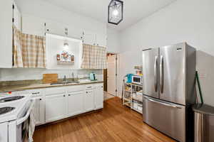 Kitchen featuring freestanding refrigerator, white cabinets, light wood-style floors, and white microwave