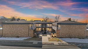 View of front of house with brick siding, stairway, a patio area, and a balcony