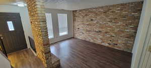 Unit #4- Foyer featuring brick wall, a textured ceiling, and wood finished floors