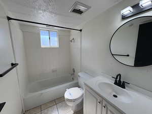 Unit #8- Bathroom with bathing tub / shower combination, vanity, a textured ceiling, and light tile patterned floors