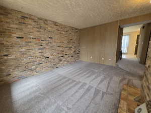 Unit #2- Spare room featuring carpet flooring, wood walls, and brick wall
