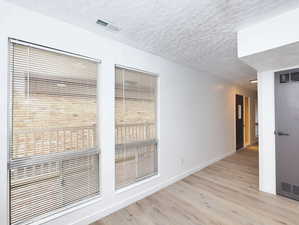 Unit #1- Unfurnished room featuring light wood finished floors and a textured ceiling