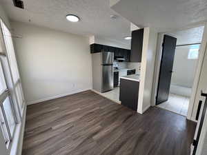 Unit #8- Kitchen with dark cabinets, a textured ceiling, light countertops, freestanding refrigerator, and light wood-style flooring