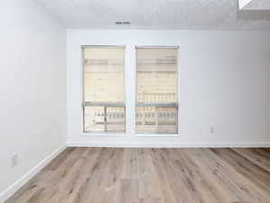 Unit #1- Spare room featuring light wood-type flooring and a textured ceiling