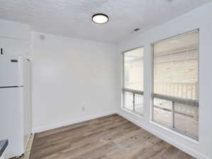 Unit #1- Unfurnished dining area featuring a textured ceiling and light wood-style flooring
