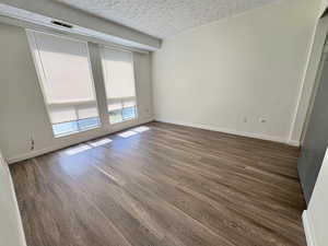 Unit #8- Spare room with a textured ceiling and dark wood finished floors