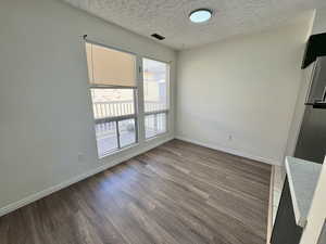 Unit #8- Unfurnished dining area featuring wood finished floors and a textured ceiling