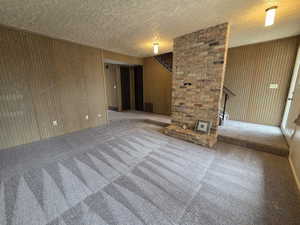 Unit #2- Unfurnished living room with wooden walls, stairs, carpet, and a textured ceiling