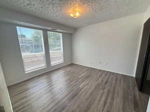 Unit #7-Spare room with dark wood-style floors and a textured ceiling