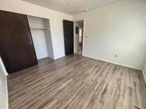Unit #7-Unfurnished bedroom with a closet, a textured ceiling, and dark wood-style flooring