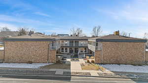 Back of property with brick siding and a balcony