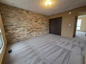 Unit #2- Unfurnished bedroom featuring wooden walls, carpet floors, and brick wall