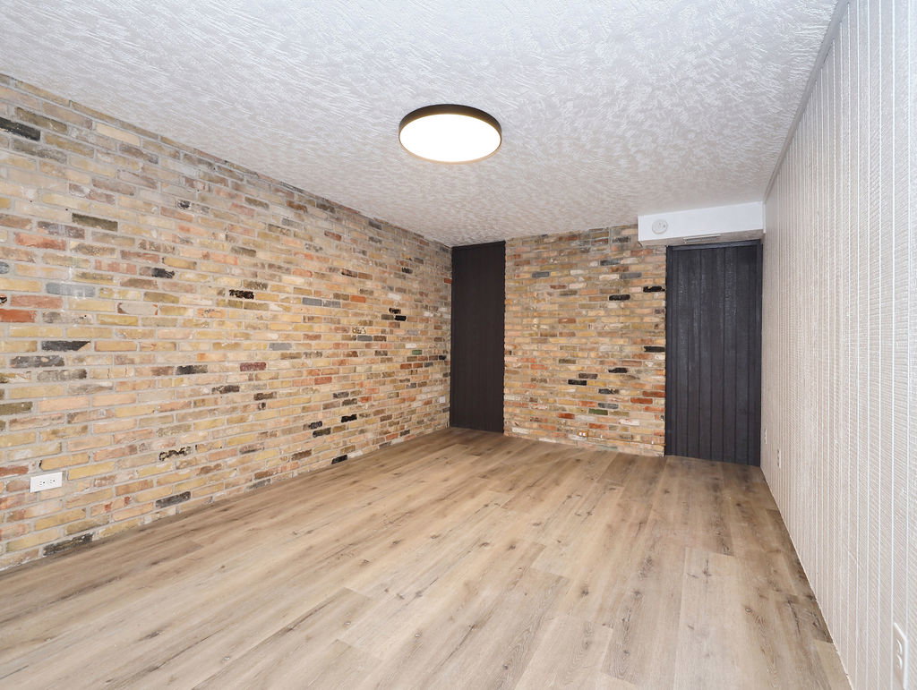 Unit #1- Empty room with light wood-style flooring and a textured ceiling