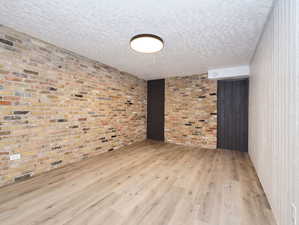 Unit #1- Empty room with light wood-style flooring and a textured ceiling