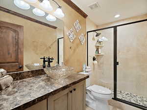 Full bathroom featuring vanity, a shower stall, ornamental molding, and a textured wall