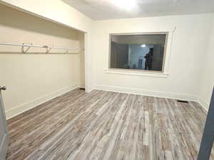Unfurnished bedroom with light wood finished floors, a textured ceiling, and a closet