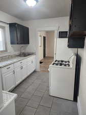 Kitchen with white appliances, light countertops, light tile patterned floors, and white cabinets