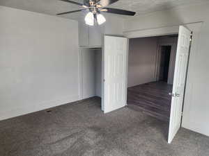 Unfurnished bedroom featuring carpet, ceiling fan, a closet, and a textured ceiling