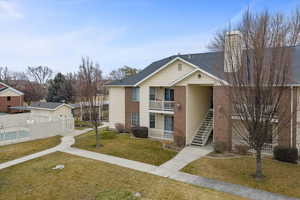 View of front of home with a chimney, stairway, brick siding, a balcony, and a shingled roof