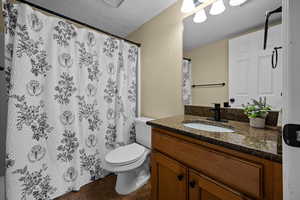 Bathroom featuring a textured ceiling, vanity, a shower with curtain, a textured wall, and dark tile patterned floors