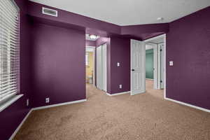 Carpeted empty room featuring a textured wall and a textured ceiling