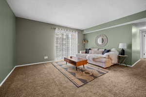 Carpeted living room featuring a textured ceiling and baseboards