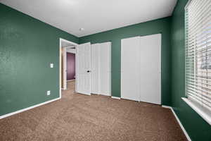 Unfurnished bedroom featuring multiple closets, carpet, a textured wall, and a textured ceiling
