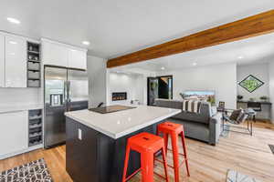 Kitchen featuring open floor plan, beamed ceiling, dual tone cabinets, stainless steel fridge with ice dispenser, and light countertops