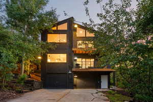 View of front of house featuring a balcony, an attached garage, and concrete driveway