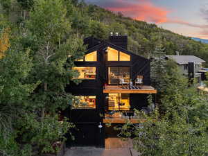 Modern home featuring a garage, a chimney, concrete driveway, and a balcony