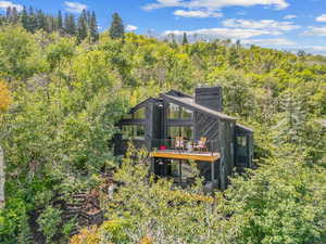 Rear view of house with a chimney, a wooden deck, and a forest view