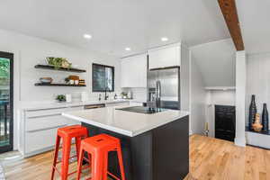 Kitchen with a center island, stainless steel fridge, open shelves, a kitchen breakfast bar, and light wood finished floors