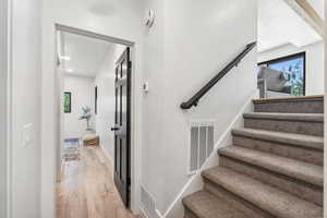 Staircase with wood finished floors and recessed lighting