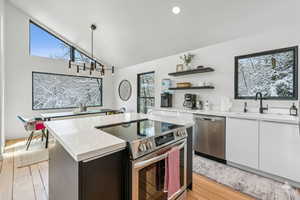 Kitchen featuring stainless steel appliances, a center island, vaulted ceiling, open shelves, and pendant lighting