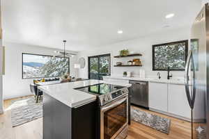 Kitchen featuring appliances with stainless steel finishes, light wood finished floors, a center island, white cabinetry, and open shelves