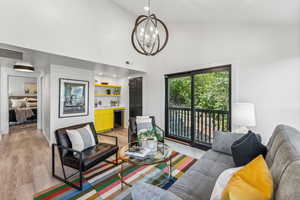 Living room with light wood-type flooring, hanging lights, beverage cooler, and vaulted ceiling