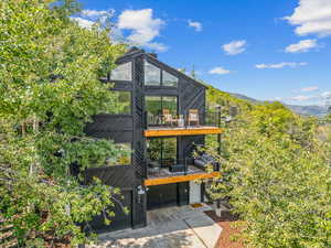 Back of house featuring an attached garage, concrete driveway, a mountain view, and a balcony