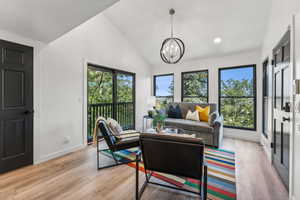 Living room featuring lofted ceiling, light wood-type flooring, and suspended lighting