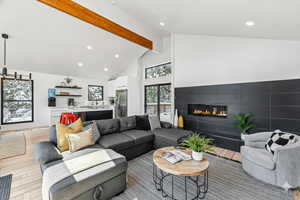 Living area featuring high vaulted ceiling, light wood-type flooring, a fireplace, recessed lighting, and beamed ceiling