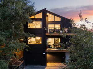 View of front of property featuring an attached garage, a balcony, and driveway