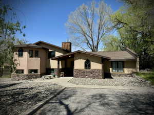 View of front of property with stucco siding, a chimney, and stone siding