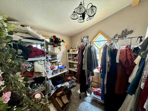 Spacious closet featuring a chandelier, carpet floors, and vaulted ceiling