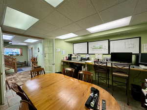 Dining room with a drop ceiling, stone tile floors, and an office area