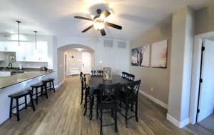 Dining area featuring arched walkways, light wood-type flooring, a ceiling fan, and radiator