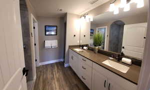Bathroom with double vanity and dark wood-style floors