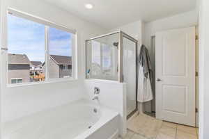 Full bath featuring a shower stall, a garden tub, and light tile patterned floors