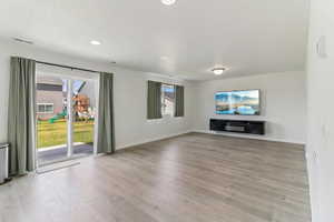 Unfurnished living room with healthy amount of natural light, light wood finished floors, and recessed lighting