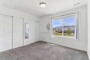 Unfurnished bedroom with multiple closets and carpet