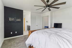 Bedroom featuring a ceiling fan, light carpet, and ensuite bathroom
